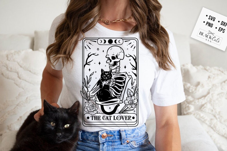 Puede incluir: Una ilustraci&oacute;n en blanco y negro de un esqueleto sosteniendo un gato negro. La ilustraci&oacute;n est&aacute; rodeada de flores y estrellas. El texto "The Cat Lover" est&aacute; debajo de la ilustraci&oacute;n.