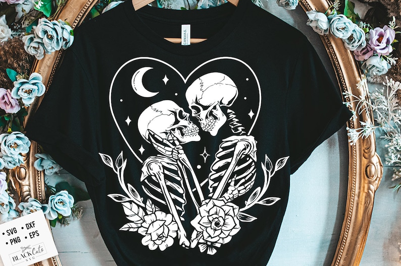 May include: Black t-shirt featuring a white graphic of two skeletons embracing within a heart, adorned with flowers and a crescent moon. The text "Black Cats SVG" is at the bottom of the image.