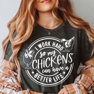 May include: A dark gray t-shirt with a white circle graphic that says "I work hard so my chickens can have a better life". The graphic also includes two stylized chickens.