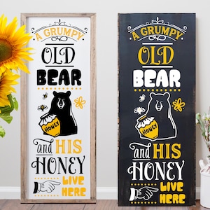 May include: Two wooden signs with a black bear and honey pot illustration. The text on the signs reads "A Grumpy Old Bear and His Honey Live Here".