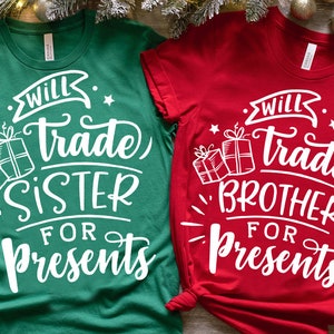 May include: Two Christmas-themed t-shirts, one green and one red, with the text "Will Trade Sister/Brother for Presents" and a graphic of wrapped gifts.