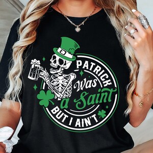 May include: Black t-shirt with a green shamrock and a skeleton holding a beer mug. The text on the shirt reads "Patrick Was a Saint But I Ain't".