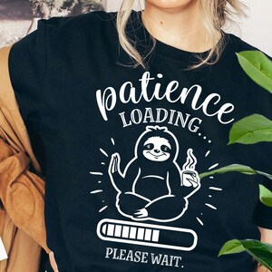May include: Black t-shirt with a white graphic of a sloth meditating and holding a cup of coffee. The text "patience loading... please wait." is printed below the sloth.