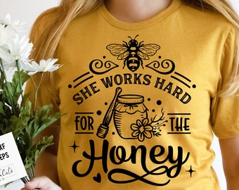 May include: A yellow t-shirt with a black graphic design that says "She works hard for the honey" with a bee and a jar of honey.