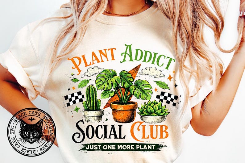 May include: Cream-colored t-shirt with a graphic featuring the text "PLANT ADDICT SOCIAL CLUB" and illustrations of plants, including a cactus, a monstera, and a succulent. The design includes clouds, stars, and checkered flags.