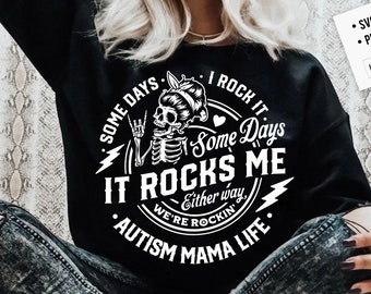 Może przedstawiać: Czarno-biały projekt graficzny ze szkieletem w kokardce, który pokazuje znak rock and roll. Tekst brzmi "Some days I rock it, some days it rocks me, either way we're rockin' Autism Mama Life."