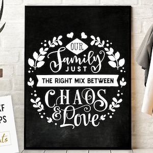Op de afbeelding: Een zwart en wit krijtbord met een witte krans en de tekst "Onze familie gewoon de juiste mix tussen chaos & liefde".