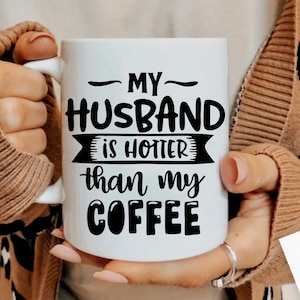 May include: White coffee mug with black text that reads "My Husband is Hotter than my Coffee".