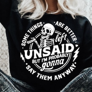 Puede incluir: Diseño gráfico en blanco y negro con un esqueleto con un globo de diálogo que dice "Algunas cosas es mejor dejarlas sin decir, pero probablemente las diga de todos modos."