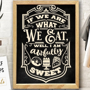 以下が含まれることがあります： 「IF WE ARE WHAT WE EAT, WELL, I AM awfully SWEET」のテキストが入った、額縁に入った黒板スタイルの看板。ドーナツ、ケーキ、ケーキのスライスのイラストが特徴です。フレームはライトブラウンです。