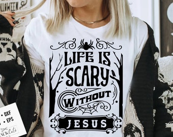 May include: A white t-shirt featuring a black graphic design that reads "Life is Scary Without Jesus". The design is in a vintage style with a spider, a bird, and a spiderweb.