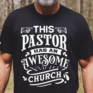 May include: A black t-shirt with white text that reads "This Pastor Has An Awesome Church".