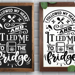 May include: Two black framed signs with white text that reads "I followed my heart and it led me to the fridge". The signs have a decorative design around the text and a picture of a refrigerator with a snowflake on it.