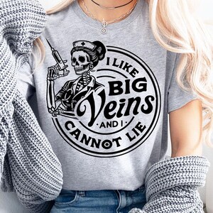May include: A gray t-shirt with a black and white graphic of a skeleton nurse holding a syringe. The graphic says "I like big veins and I cannot lie."
