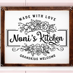 May include: A black and white sign with the text "Made with Love" above a floral design and the text "Noni's Kitchen" in a decorative font. Below the floral design is the text "Grandkids Welcome".