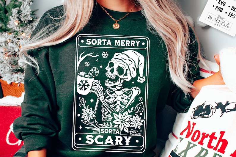 May include: A green sweatshirt with a white graphic of a skeleton wearing a Santa hat and holding a mug of hot cocoa. The graphic is surrounded by a white border and includes the text "Sorta Merry" and "Sorta Scary".