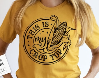 May include: A yellow t-shirt with a black circle design that says "This is my crop top" with a corn cob and husk illustration inside the circle.