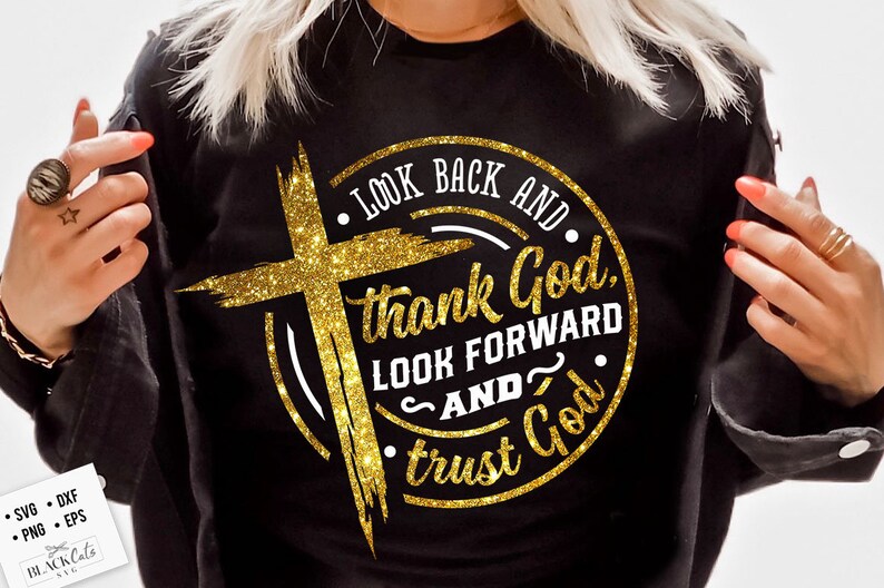Może przedstawiać: Czarna bluza z złotym brokatowym krzyżem i napisem "LOOK BACK AND thank God, LOOK FORWARD AND trust God." Projekt jest okrągły z nakładką w kształcie krzyża.