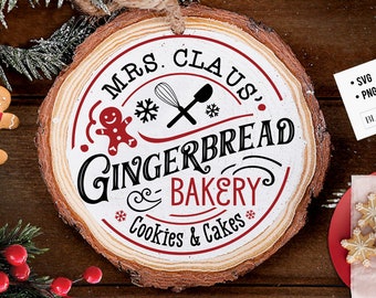 Op de afbeelding: Een rond houten bord met de tekst "MRS. CLAUS' GINGERBREAD BAKERY Cookies & Cakes" in zwart en rood. Het bord toont een peperkoekmannetje, sneeuwvlokken en keukengerei. Een kleine kaart met "SVG, DXF, PNG, EPS" staat op de achtergrond.