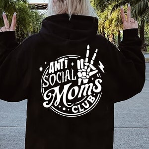 May include: Black hoodie with a white graphic design that says "Anti Social Moms Club" with a skeleton hand making a peace sign.