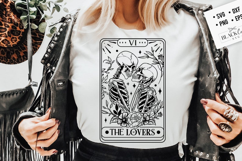 Puede incluir: Una ilustraci&oacute;n en blanco y negro de la carta del tarot de Los Enamorados que presenta dos esqueletos abraz&aacute;ndose. La carta est&aacute; enmarcada con un borde negro y el texto "VI" y "THE LOVERS" est&aacute; impreso en negro.