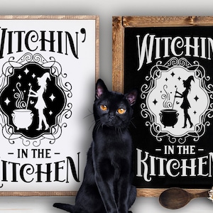 Könnte beinhalten: Zwei schwarz-weiße Schilder mit dem Text "Witchin' in the Kitchen" und einer Silhouette einer Hexe, die einen Kessel umrührt. Die Schilder sind in Holz gerahmt und haben einen rustikalen Look.