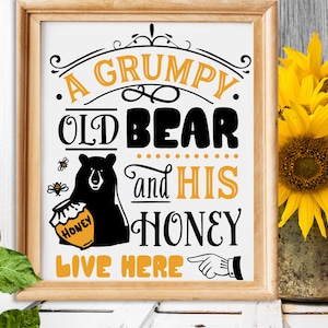 May include: A framed sign with a black bear holding a jar of honey. The sign reads "A Grumpy Old Bear and His Honey Live Here!" with a pointing hand.