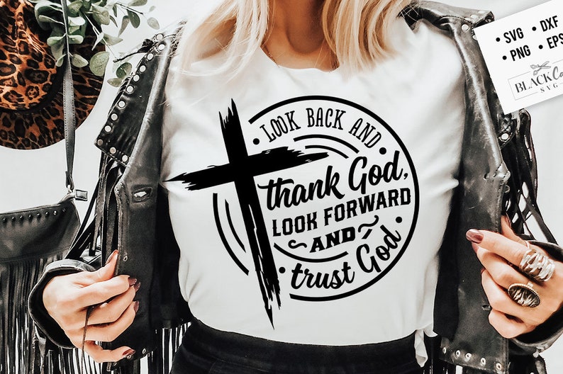 Może przedstawiać: Biała koszulka z czarnym krzyżem i napisem "LOOK BACK AND thank God, LOOK FORWARD AND trust God" w okrągłym wzorze. Obraz zawiera r&oacute;wnież czarną sk&oacute;rzaną kurtkę i kapelusz w panterkę.