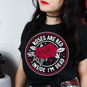 May include: Black t-shirt with a white circle graphic featuring red roses and the text "Roses are red, inside I'm dead."