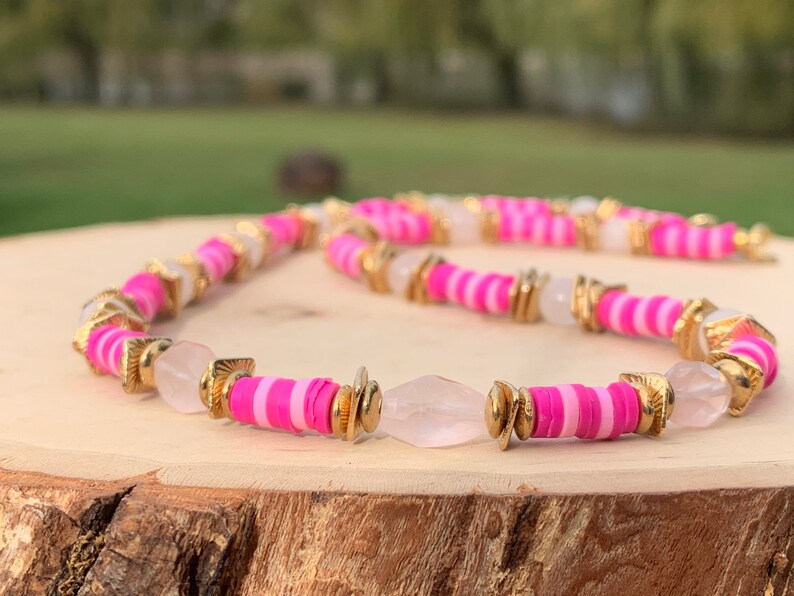 May include: A pink and white striped beaded necklace with gold accents and clear quartz beads.
