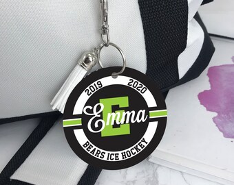 May include: Black and white round keychain with a green letter "E" and the text "Emma", "2019", "2020", "Bears Ice Hockey".