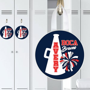 May include: A round, blue and white locker door decoration with a white megaphone and the text "AVERY" in red letters. The megaphone has a red and white pom-pom next to it. The text "BOCA Braves" is in white letters on a blue background.