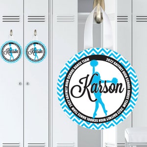 May include: A blue and white round locker door sign with a chevron pattern. The sign has a black circle in the center with the text "2022 Gaffney High School Dance Team" and a silhouette of a cheerleader with pom-poms. The name "Karson" is written in a black cursive font.