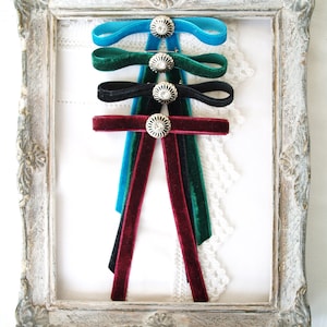 May include: Four velvet ribbon bows with decorative metal embellishments. The bows are in shades of teal, green, black, and burgundy.