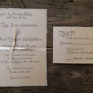 Puede incluir: Una invitaci&oacute;n de boda rectangular y una tarjeta de respuesta a juego impresas en papel texturizado de color tostado claro con bordes deshilachados. La invitaci&oacute;n est&aacute; atada con una cinta fina de color crema y presenta texto en marr&oacute;n oscuro que incluye los nombres Ray Jesse Schmuler y Jael Rangan McMillan, con la fecha 29 de noviembre de 2014.