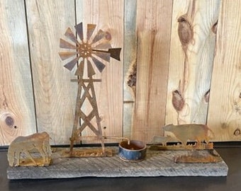 May include: Rustic metal windmill, two cows, and a candle holder on a wooden base. The metal is rusted and the wood is weathered.