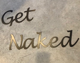 May include: Metal wall decor with the words "Get Naked" in a cursive font. The words are black and gold.