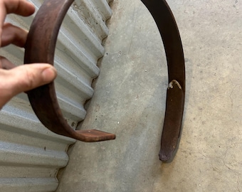 May include: A rusty metal ring, possibly a part of a wagon wheel, measuring approximately 6 inches in diameter.