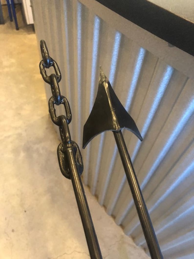 May include: A black metal anchor with a chain attached. The anchor is in the shape of a traditional ship anchor with a pointed tip and a curved arm.