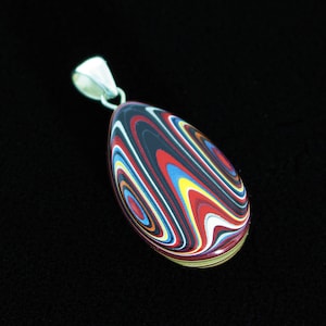 May include: A colorful, oval-shaped pendant with a silver bail. The pendant features a swirling pattern of red, black, white, blue, and yellow. The gemstone is set against a black background.