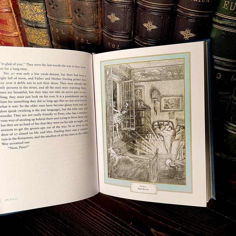 May include: An open book with a detailed illustration of a bedroom scene, framed in a light blue border. The illustration is in black and white, depicting a bed, open window, and figures. The book is surrounded by other antique books.