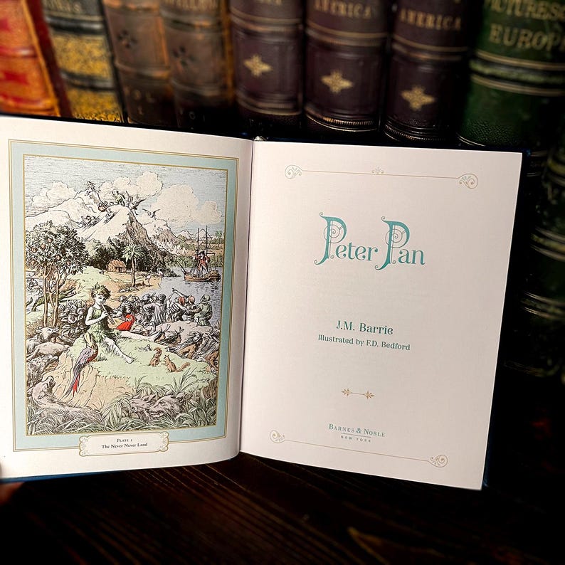 May include: An open book with the title "Peter Pan" in teal script. The left page features a colorful illustration of Peter Pan in Neverland. The right page displays the title, author, and illustrator's names, along with the publisher's logo.