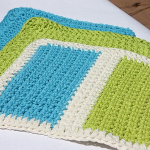 May include: Three crocheted dishcloths in blue, green, and white. The dishcloths are made with a simple stitch and have a square shape.
