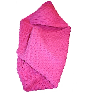 May include: A vibrant pink crocheted baby blanket with a hood. The blanket is made of soft yarn and has a textured stitch pattern. The hood is triangular and adds a cozy element to the blanket.