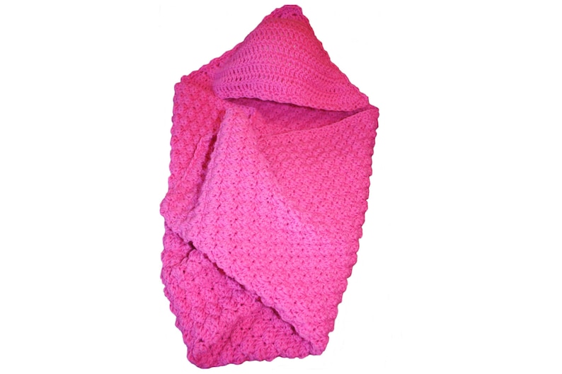 May include: A vibrant pink crocheted baby blanket with a hood. The blanket is made of soft yarn and has a textured stitch pattern. The hood is triangular and adds a cozy element to the blanket.