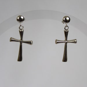 May include: A pair of silver cross earrings with a small round ball at the top of each earring.