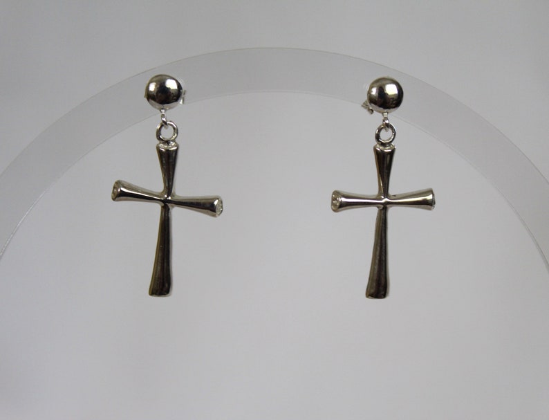 May include: A pair of silver cross earrings with a small round ball at the top of each earring.
