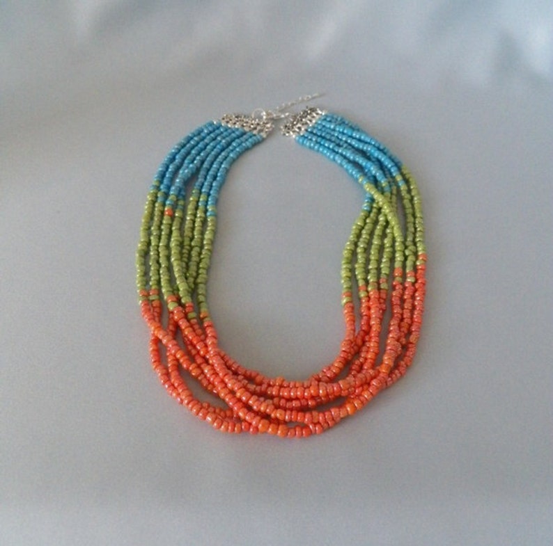 May include: Multi-strand necklace made of small beads in shades of orange, green, and blue.