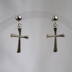 May include: A pair of silver cross earrings with a simple design. The earrings are hanging from a small ball.