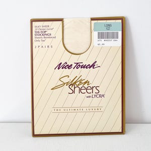 May include: A package of "Nice Touch" Silken Sheers stockings. The package is beige with a brown border and features text including "Silky Sheer," "20 Denier Lycra," and "The Ultimate Luxury." A sticker reads "Long Pearl."